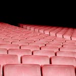 Rows of red seats in an empty auditorium with dramatic lighting.