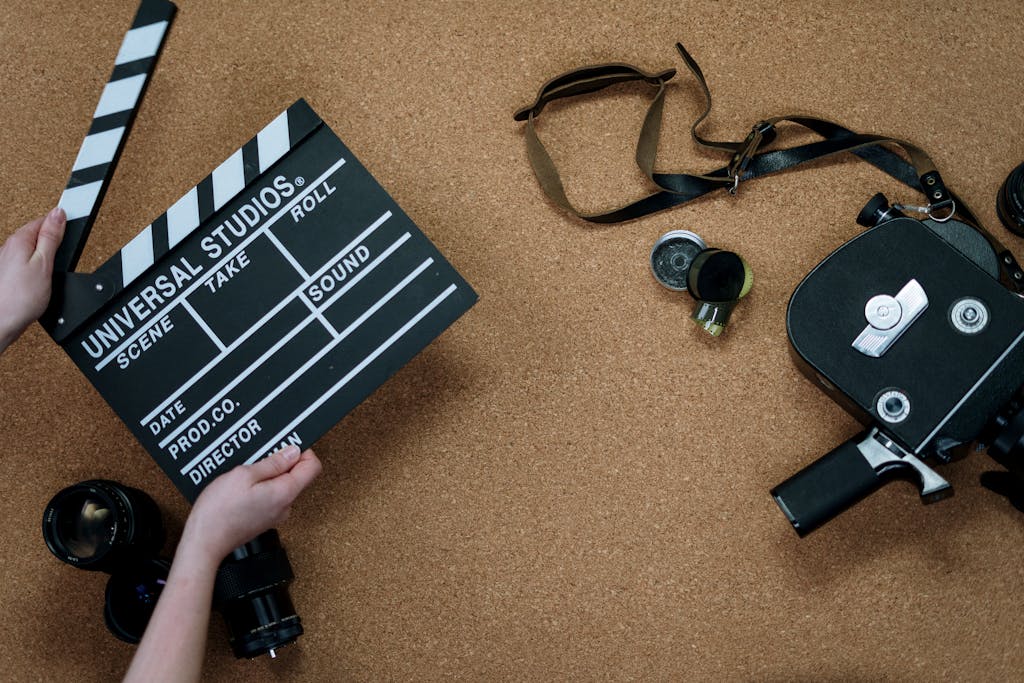 Top view of vintage film camera and clapperboard on cork background, evoking old cinema vibes.