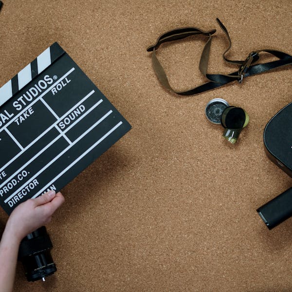 Top view of vintage film camera and clapperboard on cork background, evoking old cinema vibes.