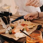 Enjoy a casual meal with wine, cheese, and snacks at an outdoor restaurant setting.